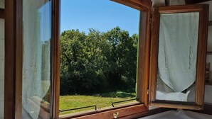 A room with a large window, wooden beams, and a bed with white bedding. - Fleur des Champs" caravan, Nordic bath and shared pool (Sigalens)