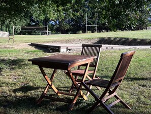 Relax in a serene outdoor setting with a table and chairs amidst lush greenery and a scenic backdrop.