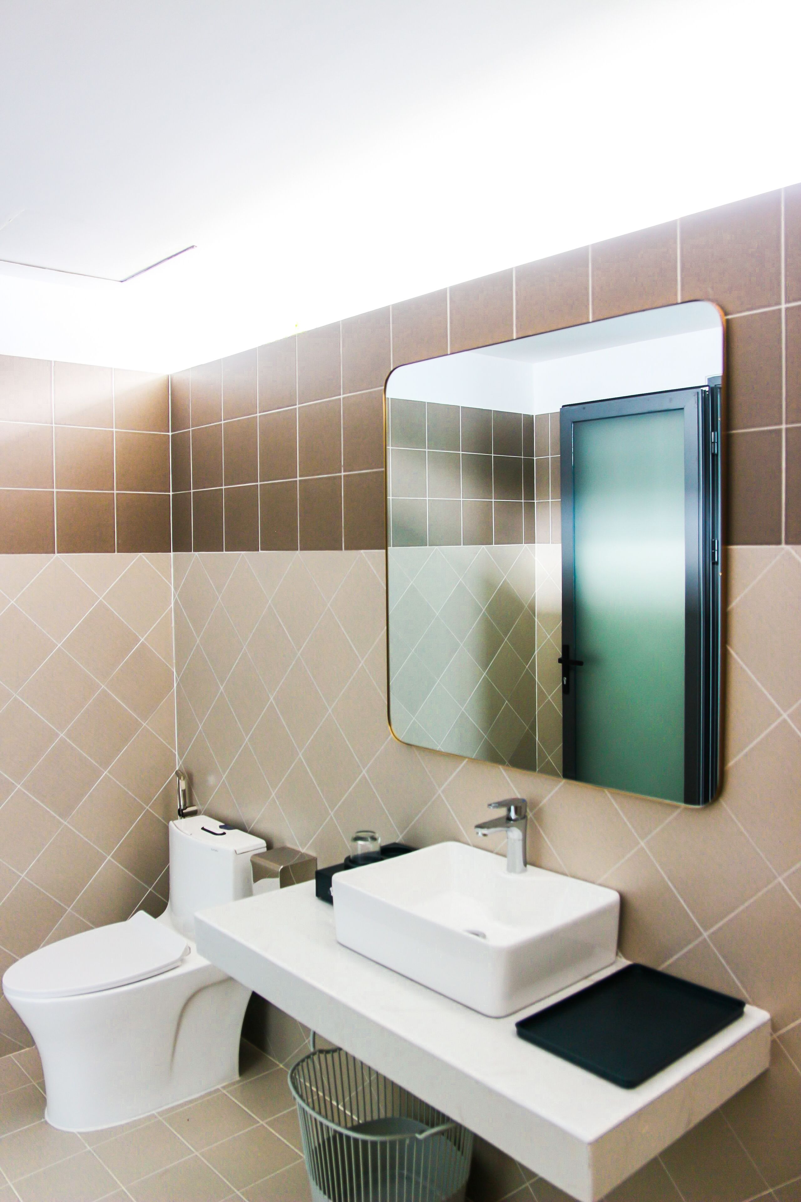 Une salle de bain moderne avec un lavabo blanc, des toilettes et un miroir au-dessus du lavabo.