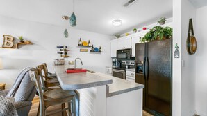 Une cuisine moderne dotée d’un îlot central, de meubles blancs et d’un réfrigérateur noir.