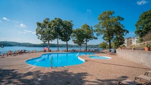 Un espace piscine comprenant plusieurs piscines, des chaises longues et des arbres.