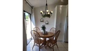 A dining area with a round table and four wooden chairs, a chandelier, and a potted plant on the wall. - Cozy Getaway 5 Min Walk to Parks (Royal Palm Beach)