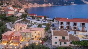 A coastal residential area with houses featuring red-tiled roofs, stone pathways, and a view of the sea. - Assos Chromata Villas (Kefalonia)