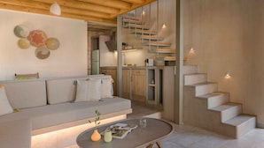 A modern interior with a sofa, a round table, and a staircase. - Assos Chromata Villas (Kefalonia)