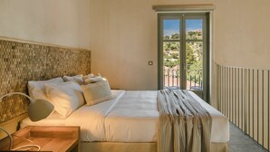 A bedroom with a bed, bedside table, lamp, and a view of a balcony with a door.