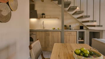 Una cocina moderna con armarios de madera, un lavamanos de acero inoxidable y una zona de comedor con mesa de madera y silla tejida.