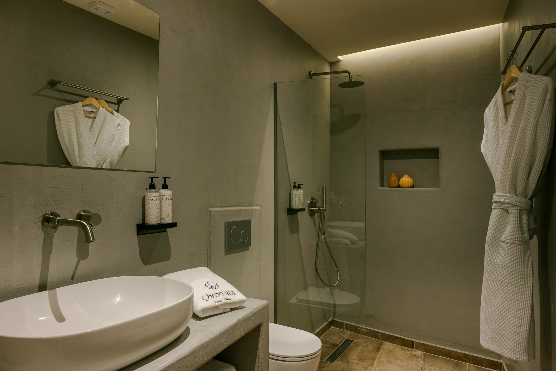 A modern bathroom with a large sink, a glass shower enclosure, and a robe rack.