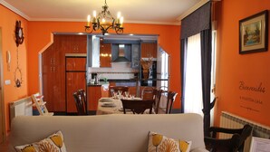 A living room with a sofa, two decorative pillows, a dining area with a table and chairs, a kitchen with cabinets and appliances, and a chandelier. - THE BLOCK I AND II (Cabornera)