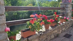 A stone wall with a wooden railing overlooking a body of water and greenery. - THE BLOCK I AND II (Cabornera)