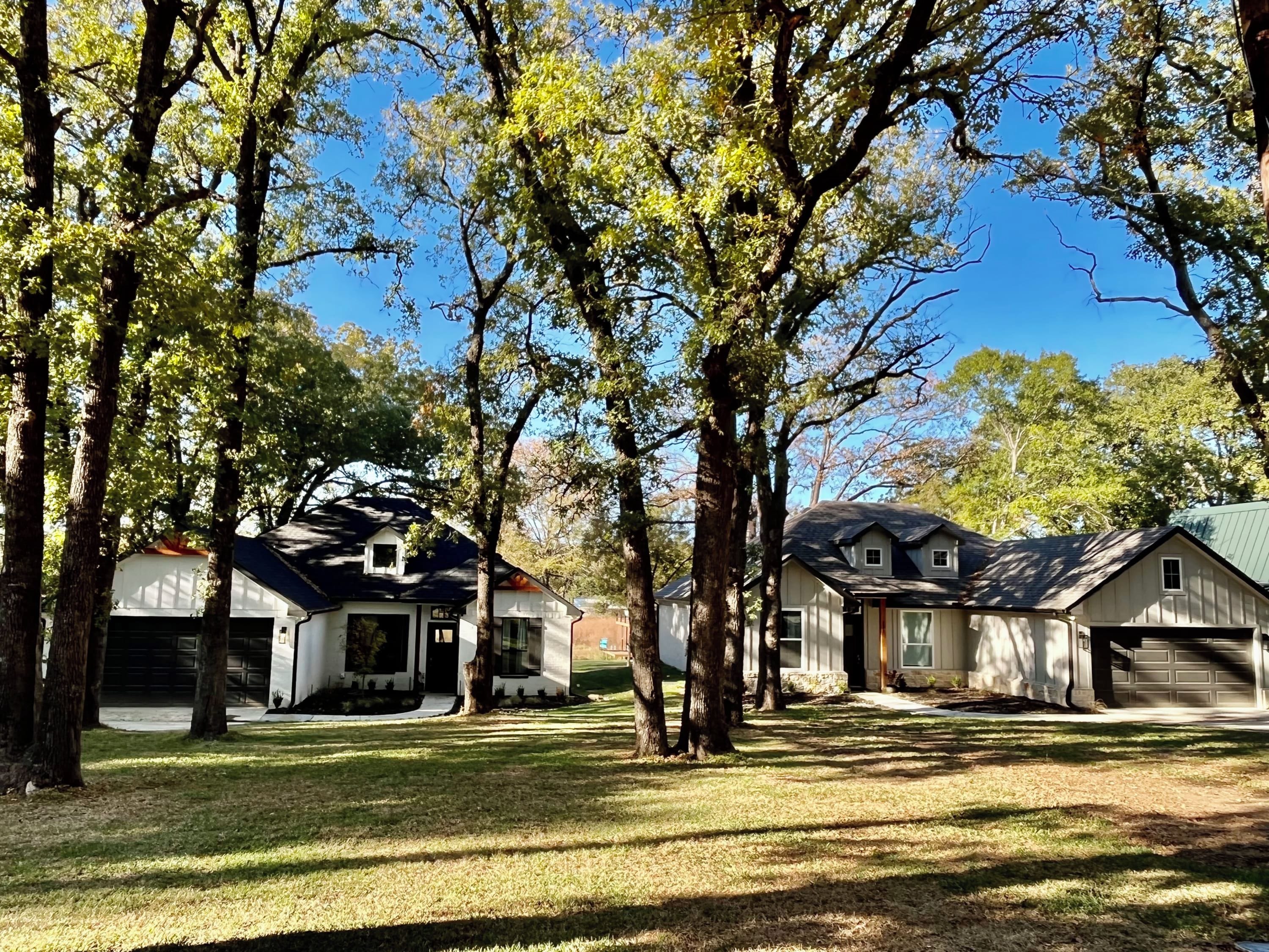 A residential area with multiple houses, each with a garage, surrounded by trees and grass.