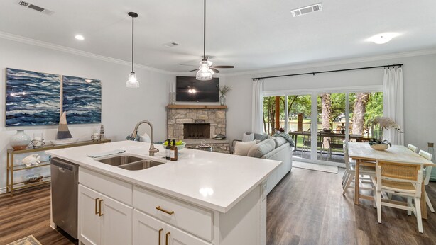 Moderni keittiö, jossa on suuri keittiösaareke, integroidut kodinkoneet ja kivinen takka.