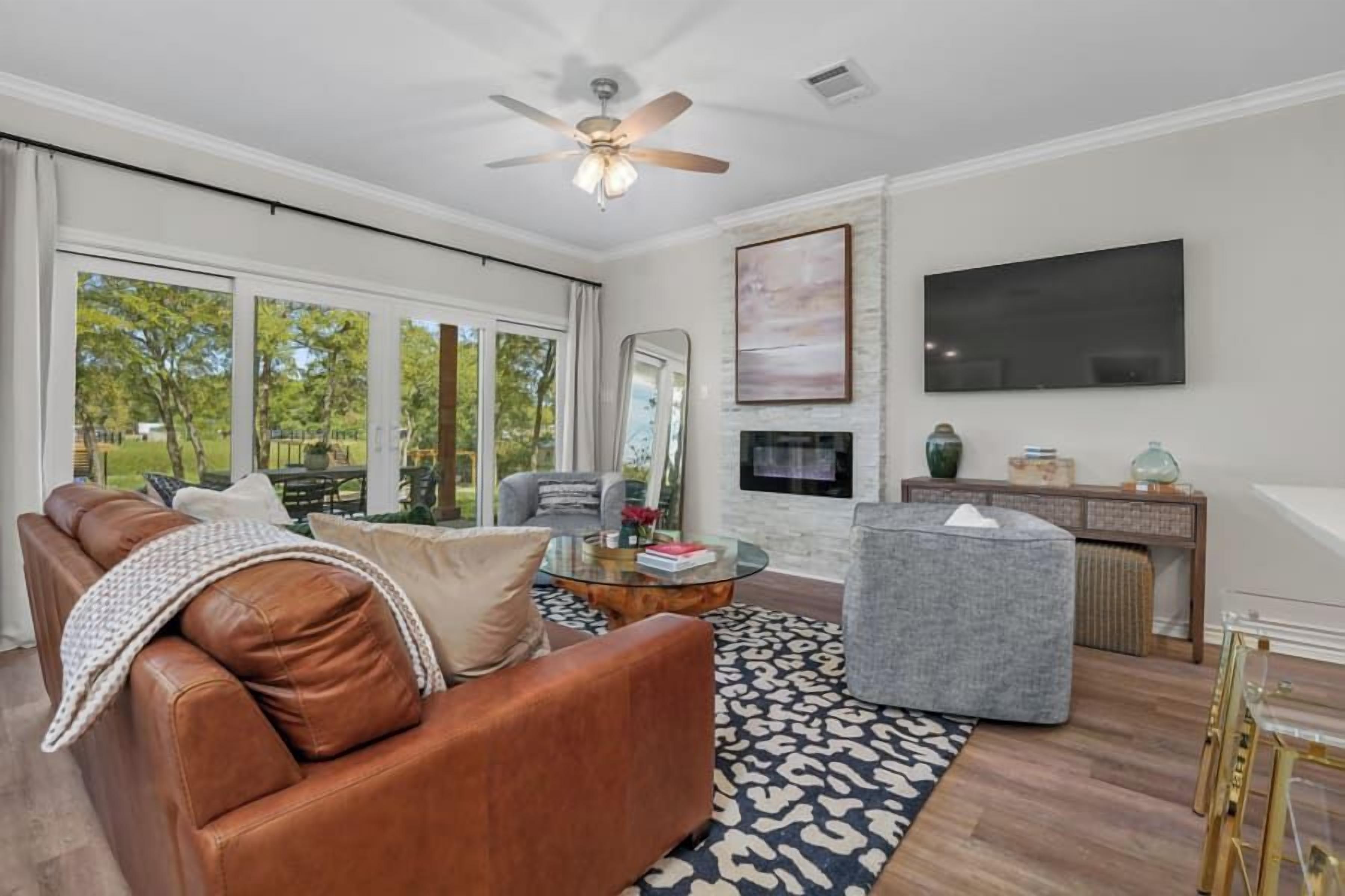 A living room with a brown leather sofa, a gray armchair, a glass coffee table, and a patterned rug.