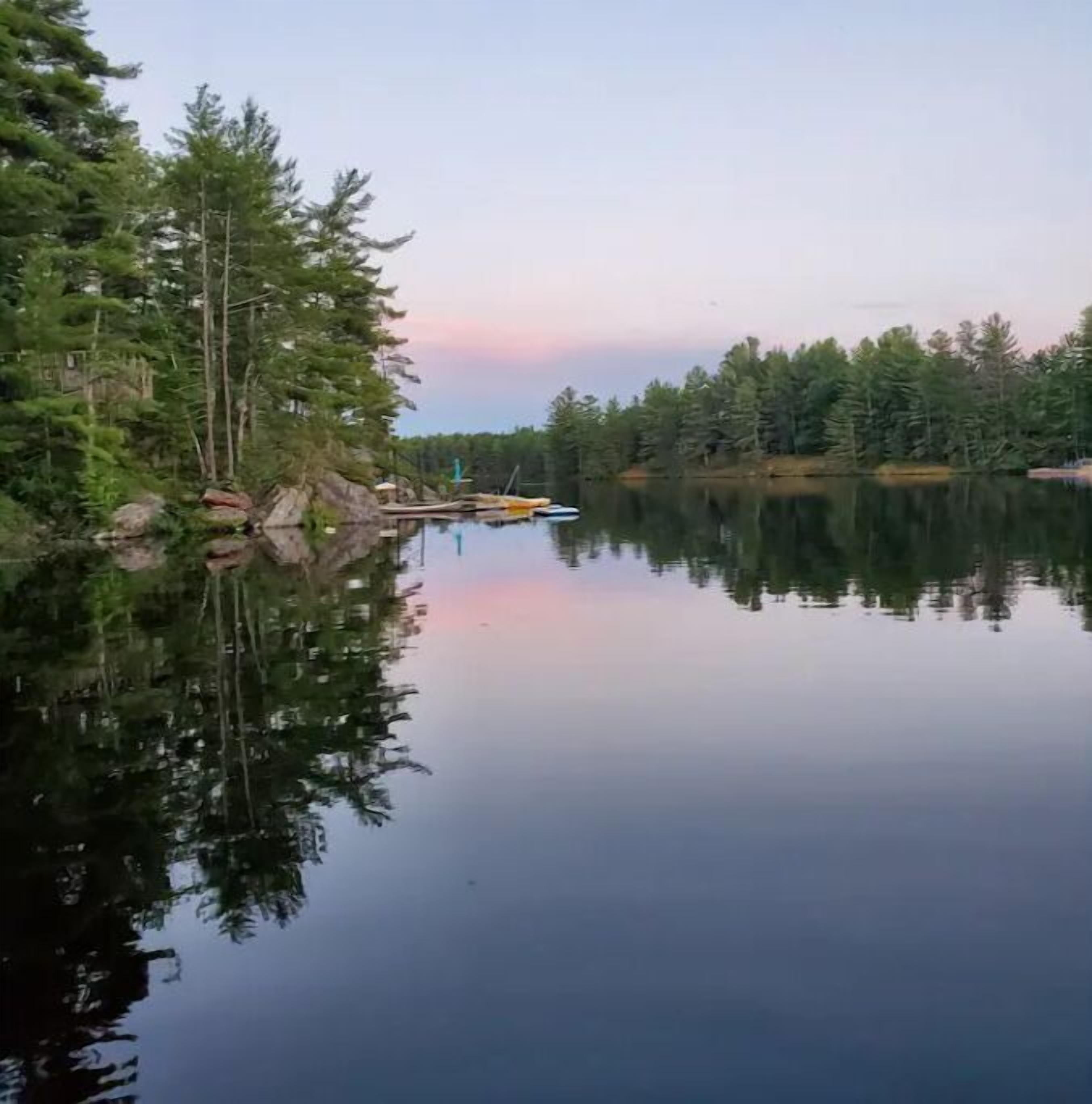 A calm lake with reflections of trees and a dock with boats.