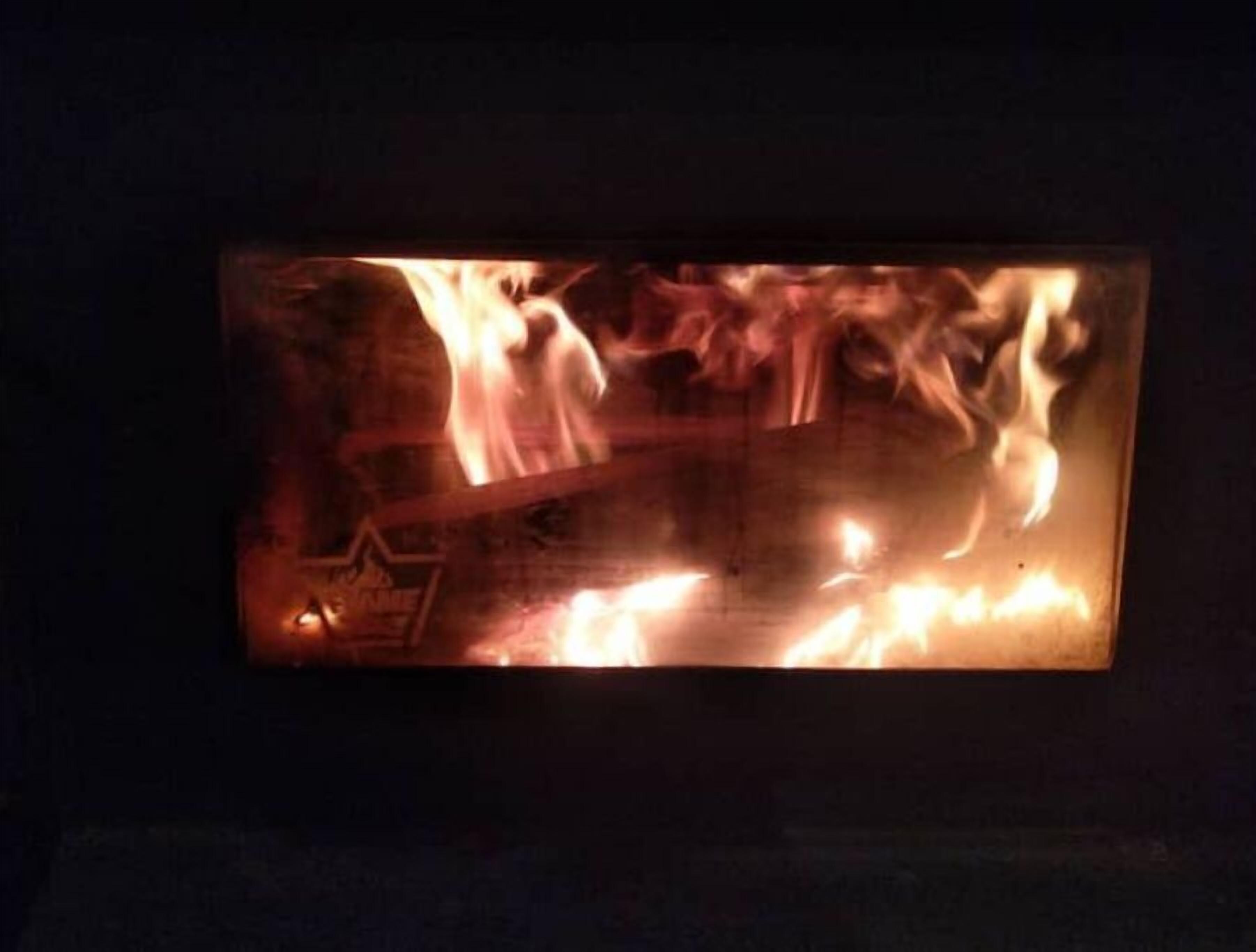 A fireplace with a log burning.