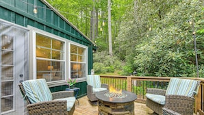 A deck with wicker furniture and a stone fire pit.