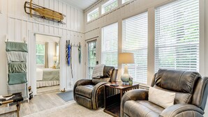 A spacious living room with leather sofas, a wooden coffee table, and a large window with blinds.