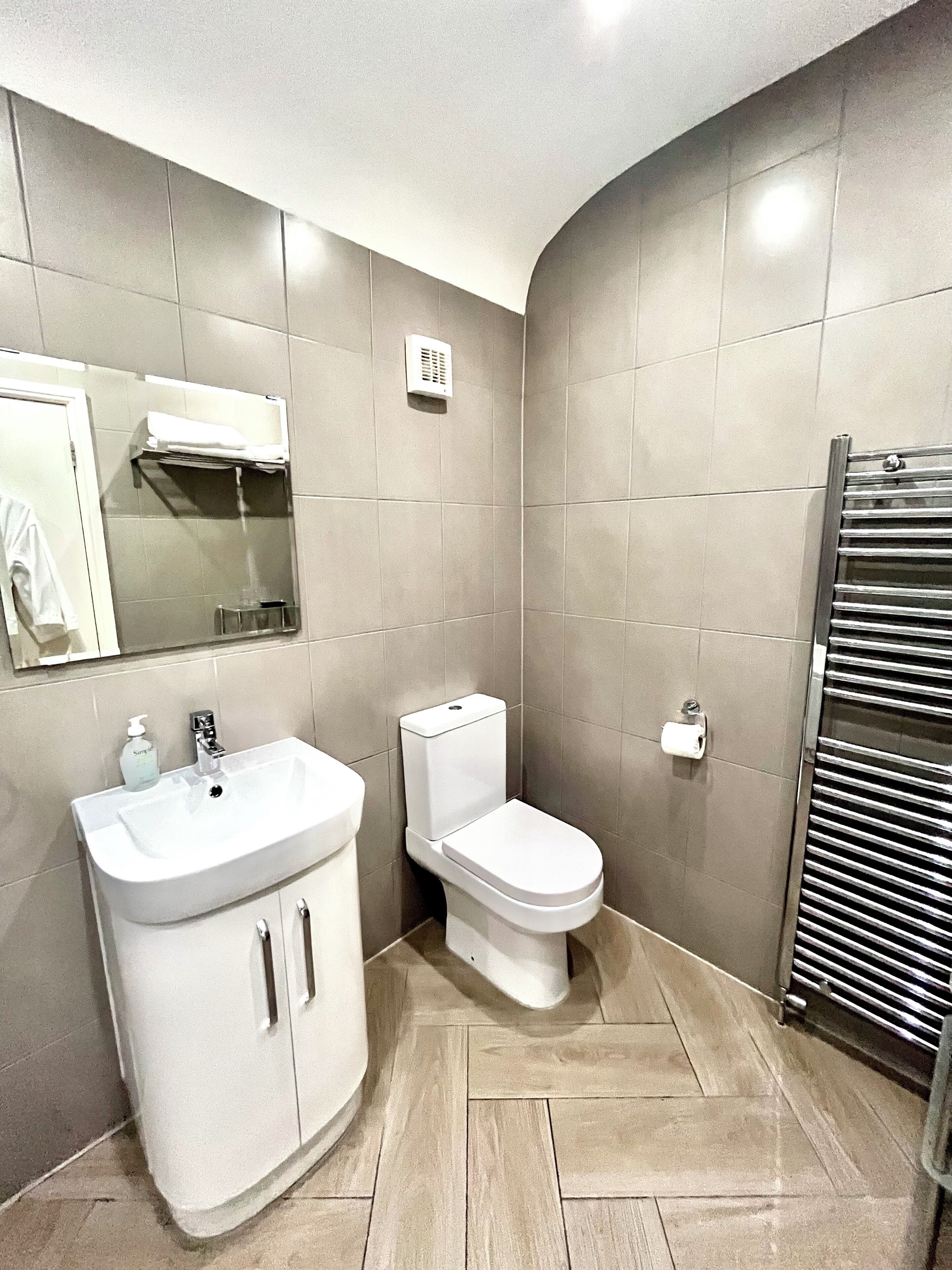 A modern bathroom with a vanity, toilet, and towel rack.