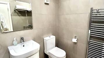 A modern bathroom with a vanity, toilet, and towel rack.