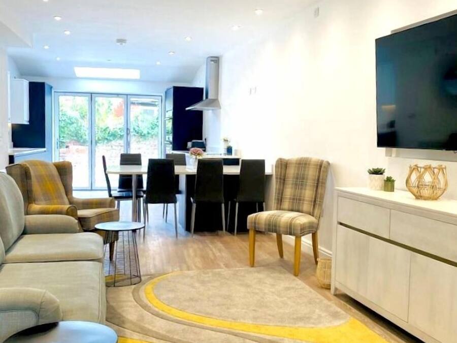 A modern living room with a sofa, chairs, a dining area, and a kitchen in the background.