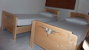 Two wooden beds with floral headboards in a room with white walls and a sloped ceiling. - Studio in the attic with car park (Ponte Arche)