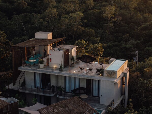 Una villa moderna con terraza en la azotea, mobiliario de exterior y piscina.