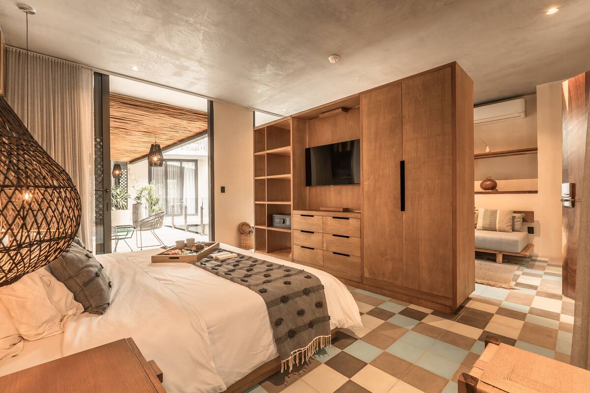 A modern bedroom with a large bed, wooden wardrobe, built-in TV, and a checkered floor.