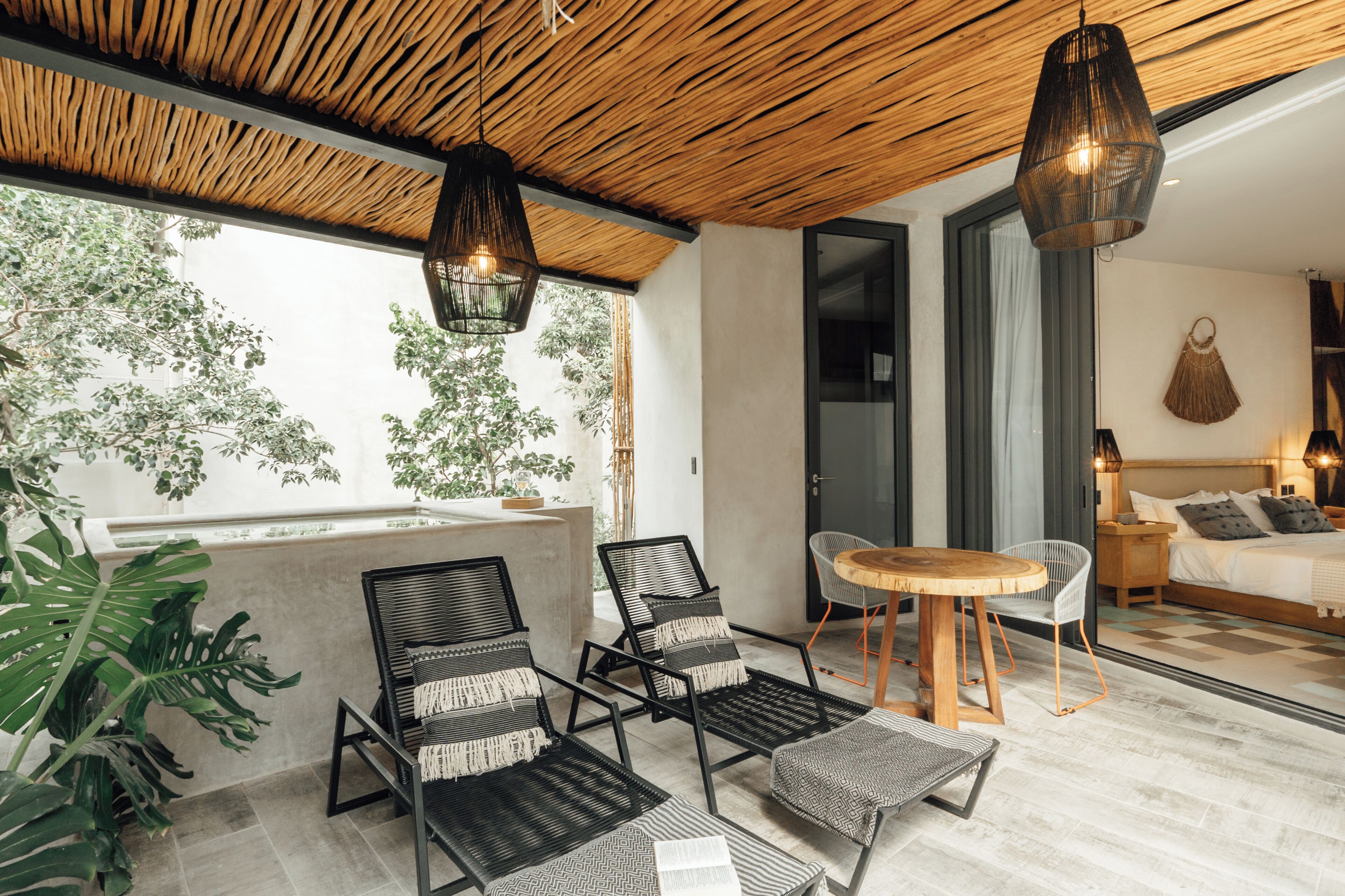 A modern room with a wooden ceiling, a dining area with a round table and chairs, and a bed with a headboard.