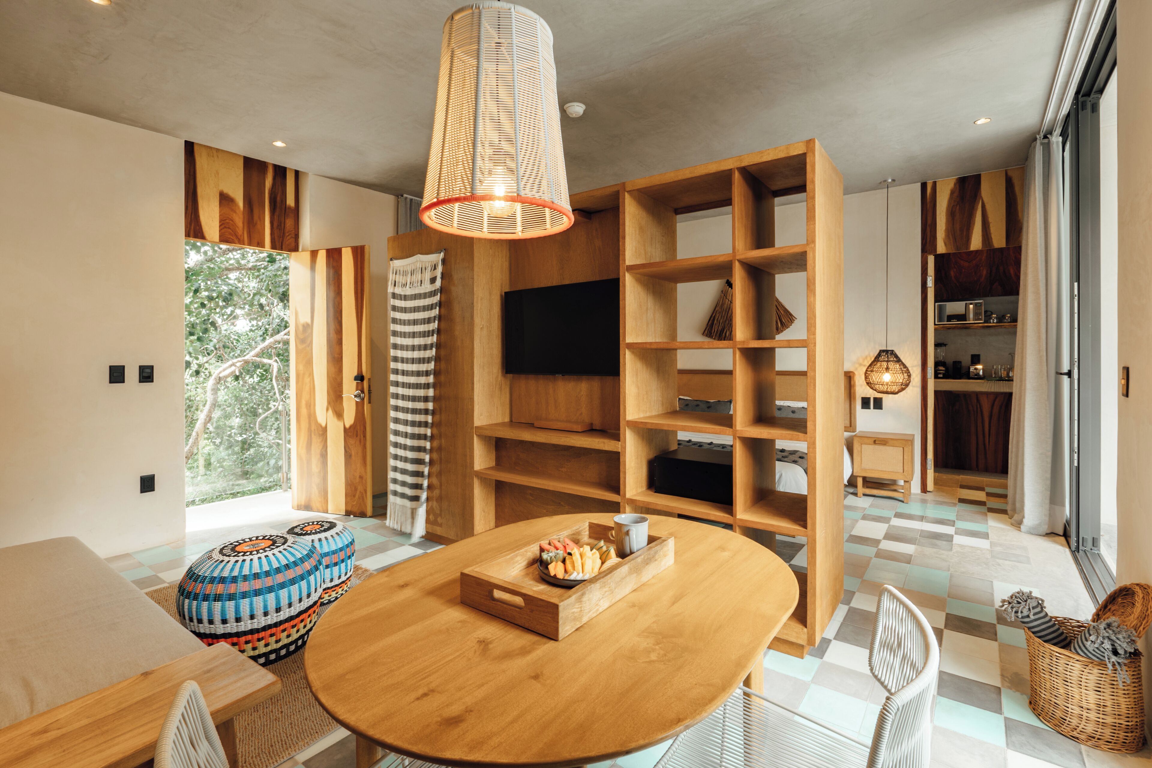 Um interior moderno com uma mesa de madeira redonda, uma televisão e estantes de madeira embutidas.