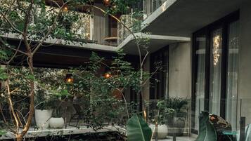 Un espace extérieur à plusieurs niveaux, agrémenté d’une végétation luxuriante, de coins salon et d’une architecture moderne.