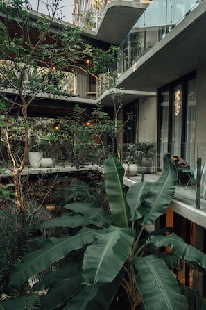 A multi-level outdoor space with lush greenery, seating areas, and modern architecture. - NAJ Boutique Hotel-Aldea Zama (Tulum)