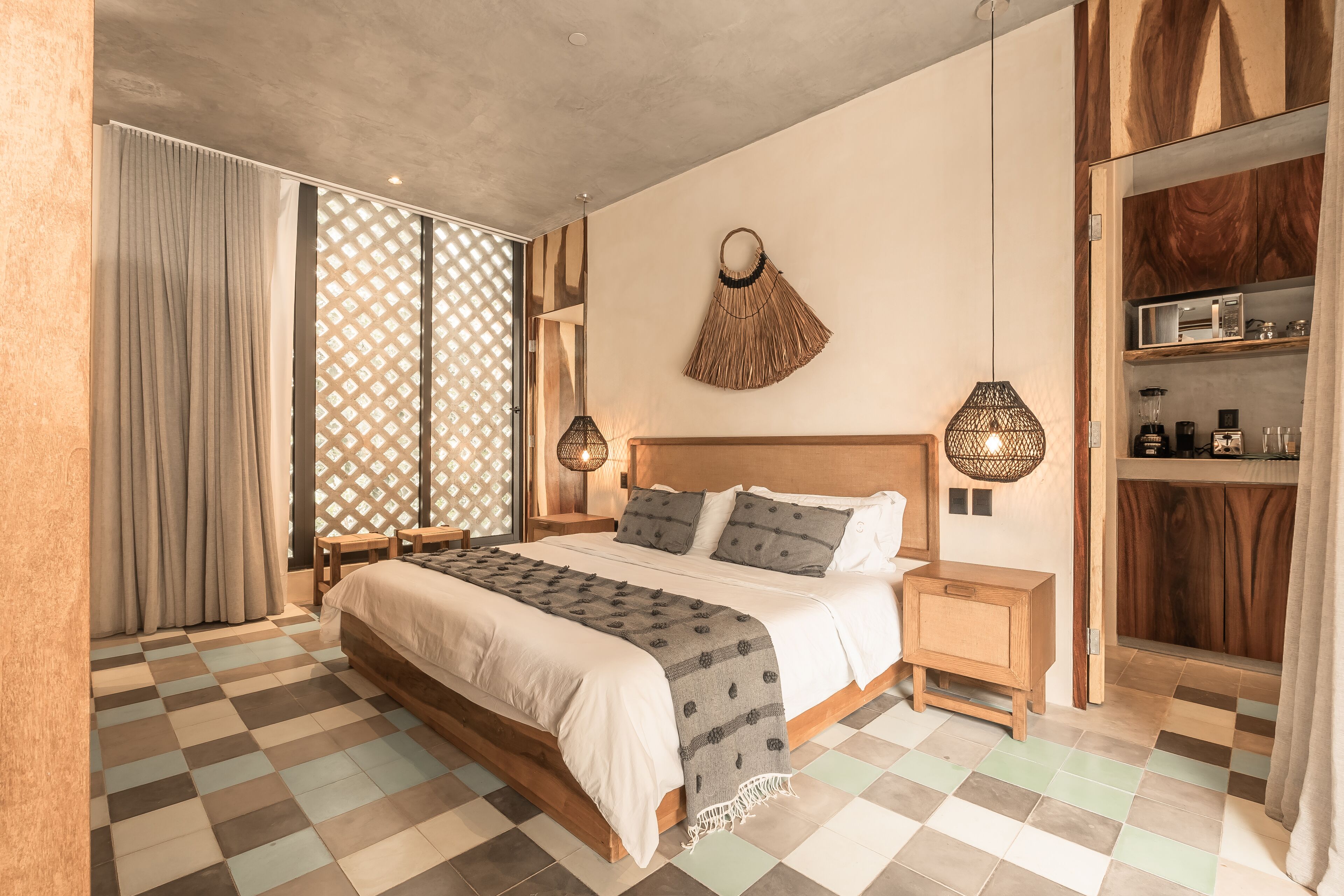 A bedroom with a large bed, wooden headboard, bedside tables, a hanging lamp, and a wardrobe.