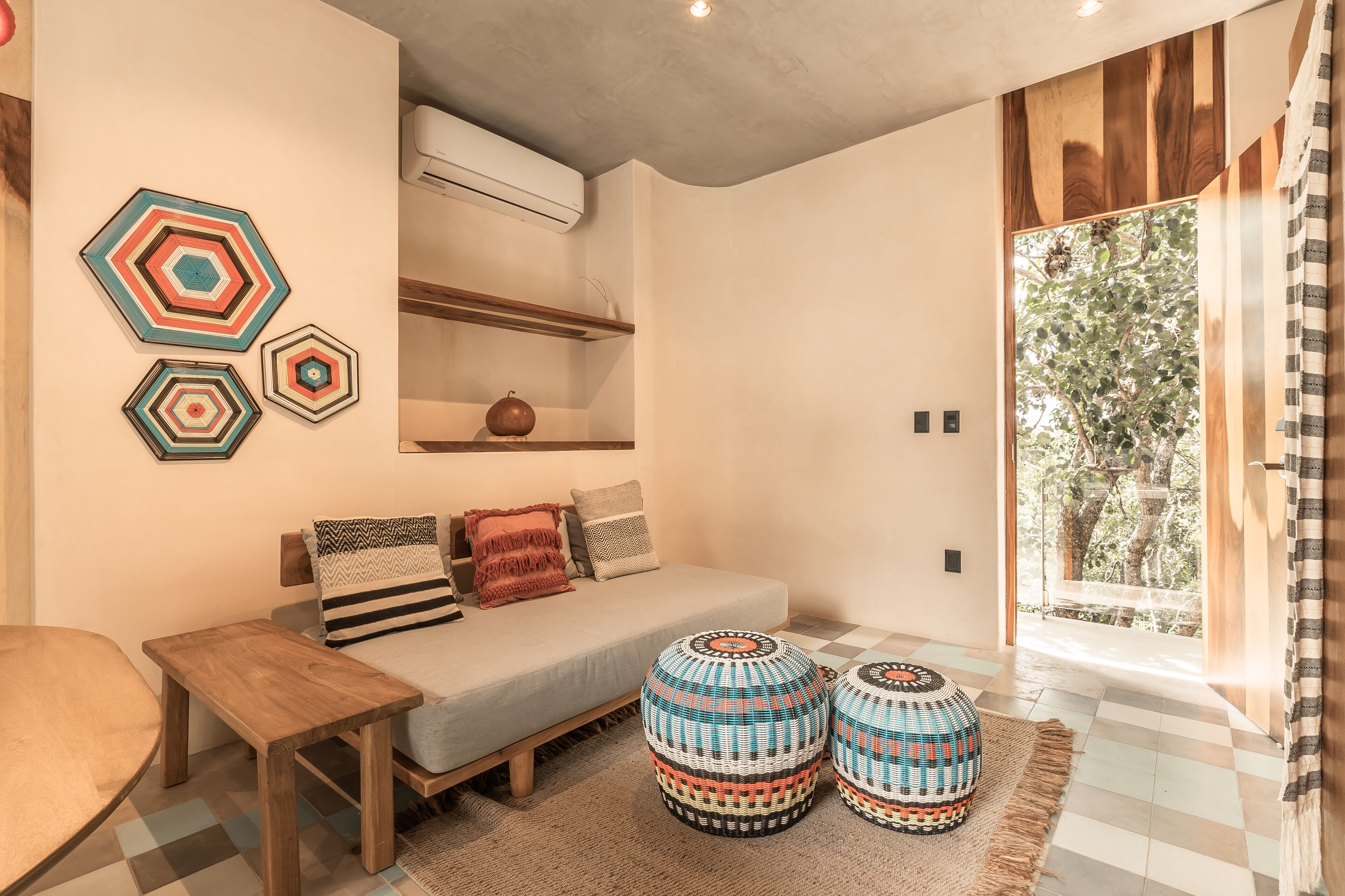 A modern living room with a sofa, ottomans, and decorative wall art.