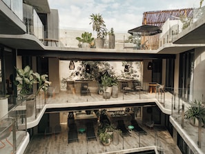 A modern multi-level outdoor lounge area with seating, potted plants, and a view of the sky. - NAJ Boutique Hotel-Aldea Zama (Tulum)