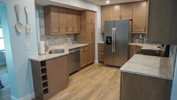 Une cuisine moderne avec des meubles en bois, un réfrigérateur en acier inoxydable et un plan de travail en marbre.