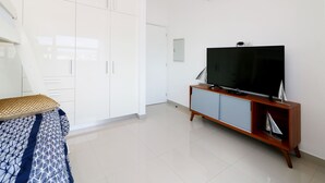 A modern living room with a large flat-screen TV, white cabinets, and a wooden entertainment unit. - Condos SVLC (Mazatlán)