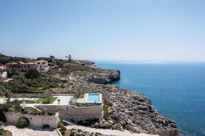 Una propiedad costera con piscina, muros de piedra y vistas al mar.