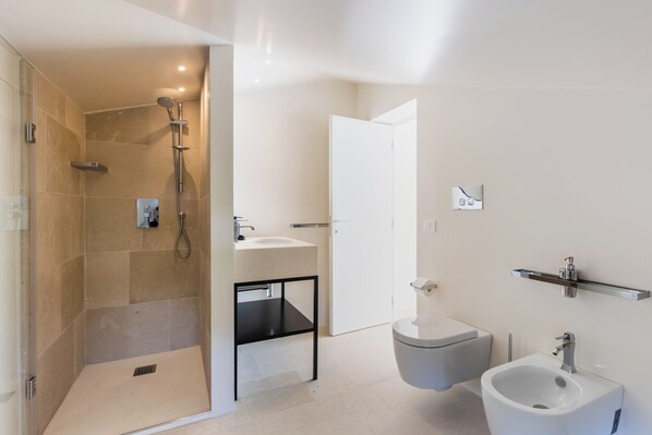 Un baño moderno con ducha, inodoro, bidé y lavabo.