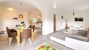A modern living space with a dining area, kitchen, and seating area. - Holiday home with pool, barbecue, outdoor kitchen and playground (Drivenik)