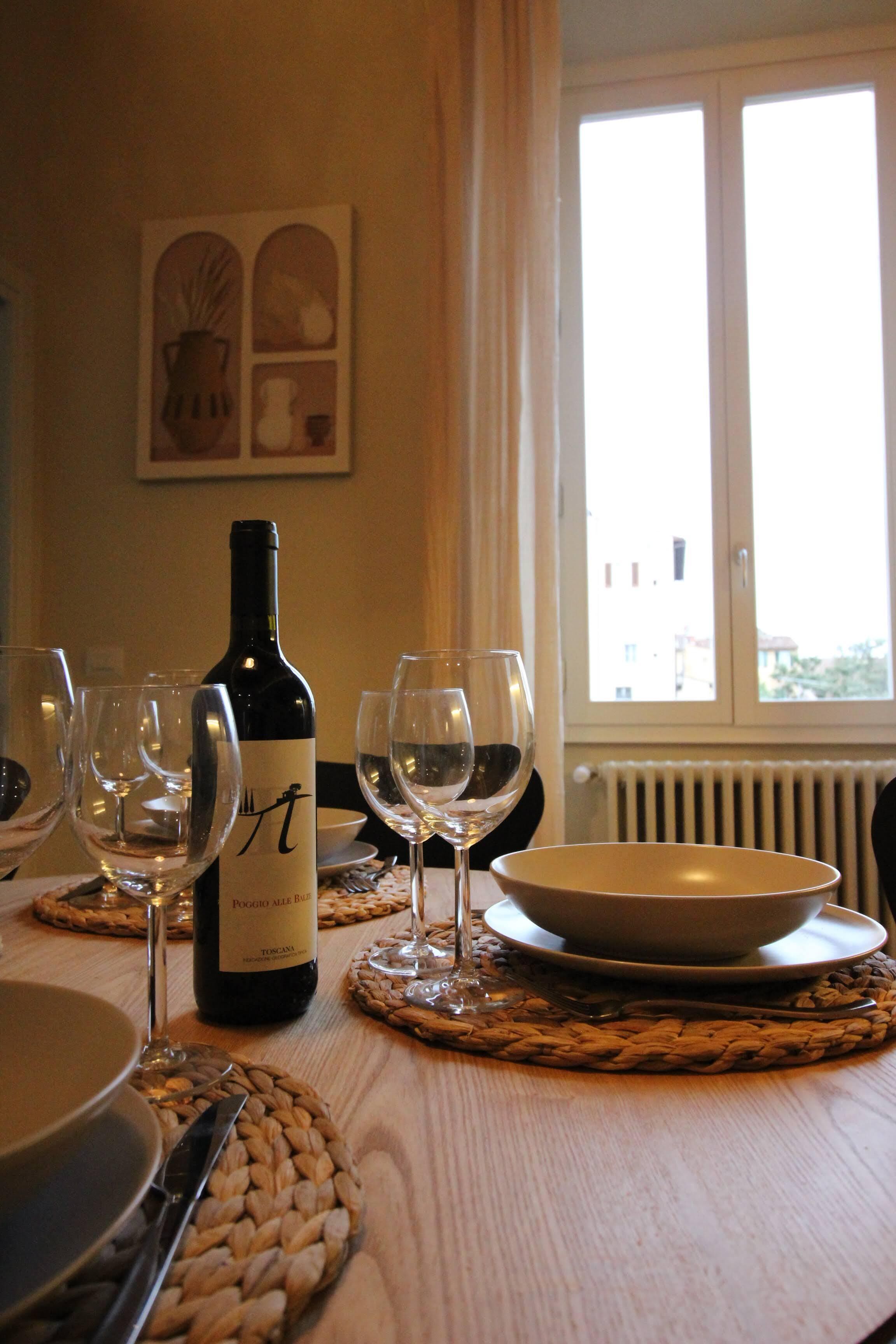 Une table à manger avec une bouteille de vin, des verres à vin vides et un bol.