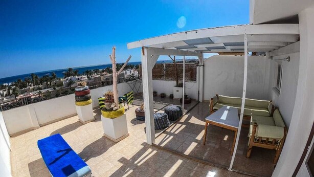 A rooftop terrace with a covered seating area, a table, and potted plants. - Cozy Rooftop LS #6 (Safaga)