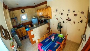A compact kitchen with wooden cabinets, a built-in microwave, and a dining area with a table set for two. - Cozy Rooftop LS #6 (Safaga)