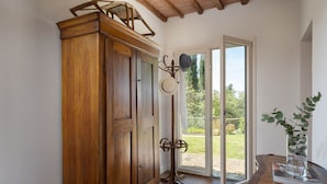 Ein Holzschrank, eine Glasvase mit einer Pflanze und eine Tür, die zu einem Außenbereich führt.