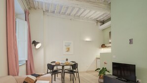 A cozy living room with a sofa, a dining table with chairs, a flat-screen TV, and a potted plant. - Apartment in Lucca with 1 bedrooms sleeps 2 (Lucca)
