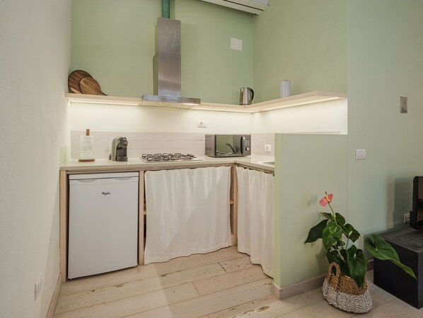 Eine kleine Küche mit Kühlschrank, Mikrowelle und Gasherd.