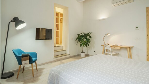 A bedroom with a bed, a desk, a chair, a potted plant, a TV, and a wardrobe. - Apartment in Lucca with 1 bedrooms sleeps 2 (Lucca)