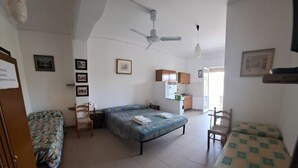 A room with a bed, a chair, a desk, a small kitchenette, and a ceiling fan. - Marina, seaside area, 5 min.walk beach, 15 min. trainstation, wi fi. parking. (Tropea)
