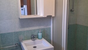 A bathroom with a white sink, a mirror, a shower enclosure, and a bidet. - Marina, seaside area, 5 min.walk beach, 15 min. trainstation, wi fi. parking. (Tropea)
