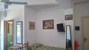 A room with a bed, a chair, a ceiling fan, a television, and a door. - Marina, seaside area, 5 min.walk beach, 15 min. trainstation, wi fi. parking. (Tropea)
