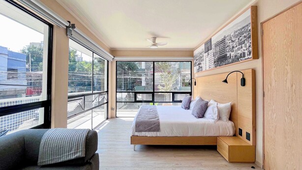 A modern bedroom with a large bed, a sofa, and a balcony with a city view. - Elegant refined stay near WTC | Terrace (Ciudad de México)