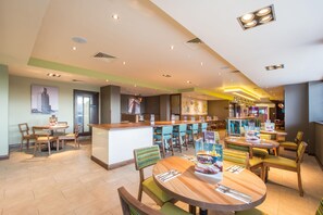 Un restaurant moderne avec des tables rondes, un bar et une vue sur le paysage urbain.